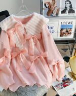 Dollcore pink sweater, a knit sweater with bows, on a hanger.