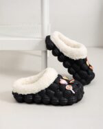 Black and white fluffy foam slippers with a textured sole and decorative accents.
