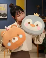 Round animal hand warmer plushies featuring a bear and penguin, perfect for warmth.