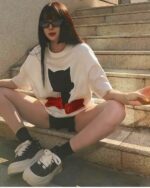 Woman wearing an astro silhouette t-shirt, white oversized tee, and sneakers.