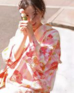 Woman wearing a pink japanese yukata with floral pattern and decorative details.