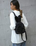Black plushie rabbit backpack worn by a woman.