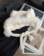White fox ears hat displayed on a laptop with magazines. Cute fox ears hat accessory.