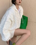 Pastel hooded sweater in a chunky knit, featuring a relaxed fit and drawstring hood.