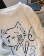White neko sweater featuring embroidered cat and star design on a fluffy fabric.