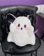 White ghost plushie backpack with purple details, sitting on a chair.