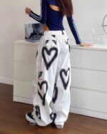 White y2k aesthetic pants with black heart spray paint design.