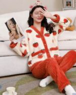Woman wearing strawberry print kawaii pajama set, soft plush material.
