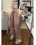 Pink cargo y2k aesthetic pants worn by a person, featuring side pockets and a relaxed fit.
