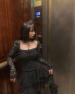 Woman wearing a lace gothic aesthetic dress in an elevator.