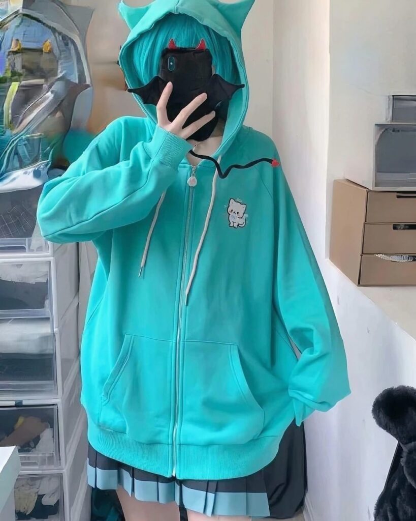 Close-up of a turquoise harajuku hoodie with cat embroidery and zipper detail.