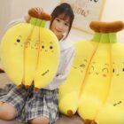 Three yellow banana plushies displayed by a person, soft and cute.