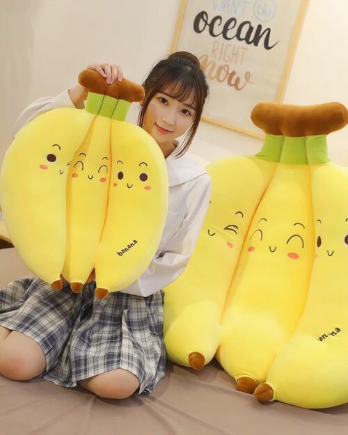 Three yellow banana plushies displayed by a person, soft and cute.