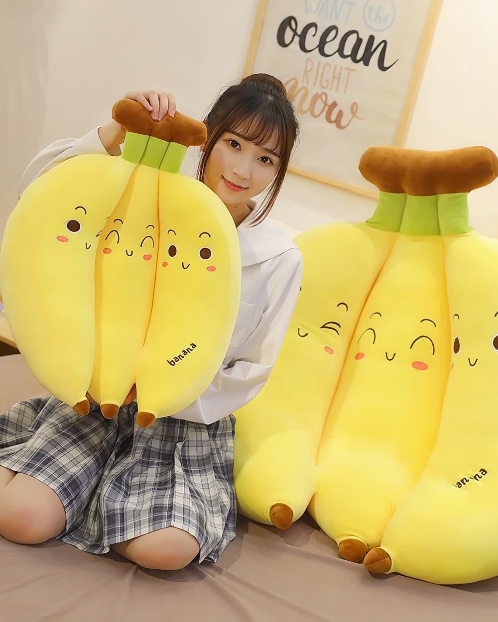 Three yellow banana plushies displayed by a person, soft and cute.