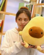 Close-up of a yellow kawaii avocado plushie held by a woman.