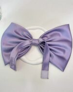 Oversize purple satin coquette bow choker with adhesive backing.