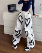 White y2k aesthetic pants with large heart and triangle spray paint designs.