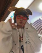 Model wearing a y2k kaomoji hoodie with cute emoji prints.