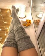 Knitxi knitted thigh high socks on legs, cozy winter style.