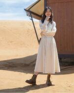 Woman wearing a beige korean style dress and Dr. Martens boots outdoors.