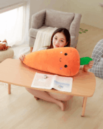 A plush kawaii carrot toy sits on a table with a woman.
