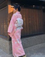 A pink traditional japanese kimono with floral patterns, worn by a woman.