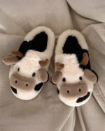 Pair of plush cow slippers featuring a cow design and brown/black color scheme.