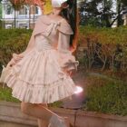 A pink floral soft girl dress with ruffles, bow, and lace details, worn outdoors.