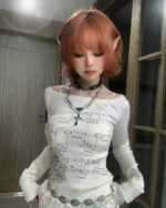 White coquette long sleeve top with musical print, featuring long sleeves and an off-the-shoulder neckline.