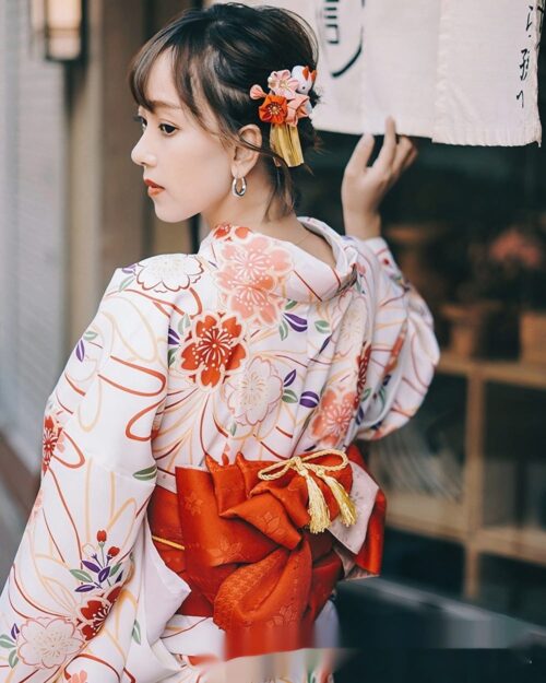 Woman wearing a floral summer anime yukata with a red obi sash, Japanese traditional garment.