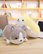 Two kawaii corgi plushies – one gray and one yellow – sitting on a wooden surface.