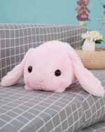 Pink big bunny plushie resting on a gray cushion.