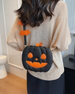 Cute black pumpkin halloween bag with orange accents, shown on a person's shoulder.