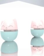 Two kawaii cat toys, a pink and blue tumbler design, are shown on a reflective surface.