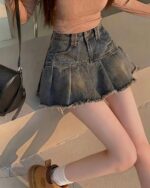 Retro Pleated Mini Skirt - Y2K aesthetic skirt in denim, featuring a gathered and frayed hemline.
