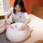 Cute white pufferfish plush toy resting on a bed, soft and huggable.