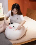 Cute white pufferfish plush toy resting on a bed, soft and huggable.