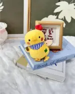 Yellow love and deepspace plushie character sitting among books and decorative items.