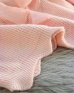 Close-up of a dollcore pink sweater, showcasing its ribbed knit texture.