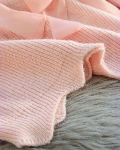 Close-up of a dollcore pink sweater, showcasing its ribbed knit texture.