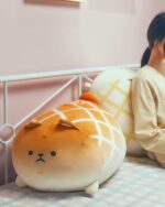 Kawaii melonwan plushie resting on a bed, featuring a rounded design and orange spots.