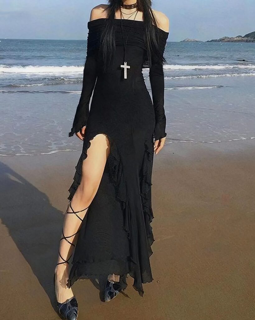 Black gothic aesthetic dress on a sandy beach with ocean waves.
