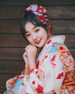Woman wearing a pink new year kimono with floral pattern and traditional Japanese hairstyle.