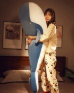 A blue kawaii whale plushie held by a woman indoors.