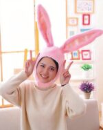 A person wearing a pink kawaii bunny ears hat, featuring plush bunny ears and a soft lining.