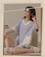 Woman wearing kawaii bear pajamas, light purple and blue design, comfy summer sleepwear.
