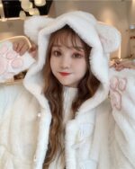 Woman wearing a white kawaii cat hoodie with cat paw accents and a fluffy hood.