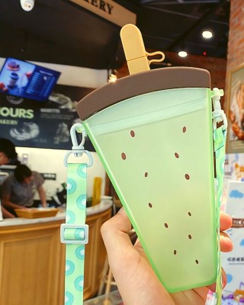 A green kawaii fruit bottle with a popsicle handle and strap.
