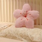 Pink sakura flower pillow resting on a floral bedspread. A sakura flower pillow.