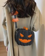 Black pumpkin halloween bag with orange accents, attached to a crossbody strap.